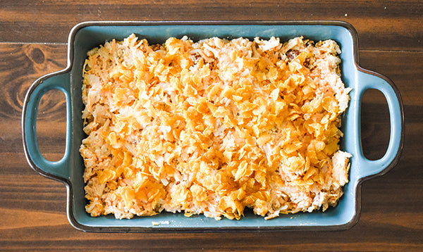 cornflake topping added on top of cheesy loaded hasbrown base in baking dish