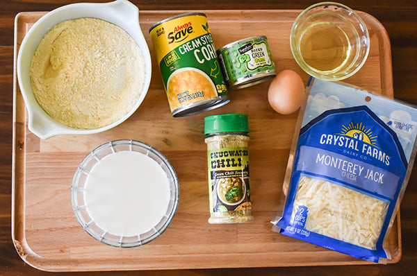 ingredients to make green chile cornbread, monterey jack cheese, milk, cream corn, egg, diced green chilies, oil, cornbread mix, and chugwater chili green chili seasoning 