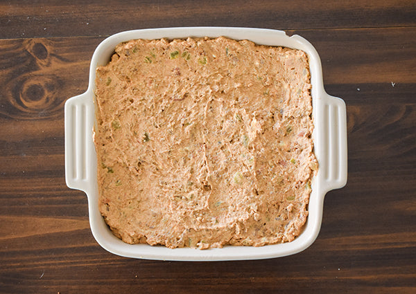 creamy fiesta bean dip in baking dish ready to bake