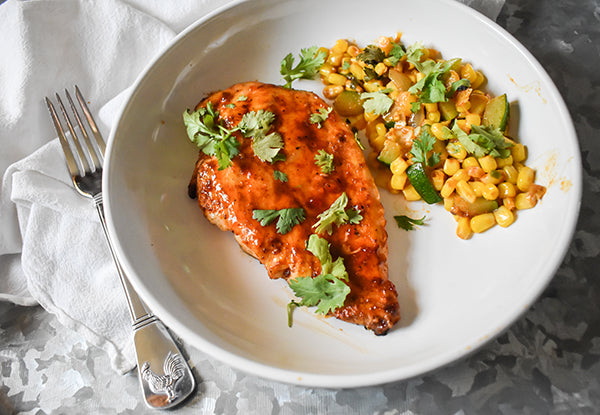 grilled sweet and spicy chicken breast on a plate with corn on the side
