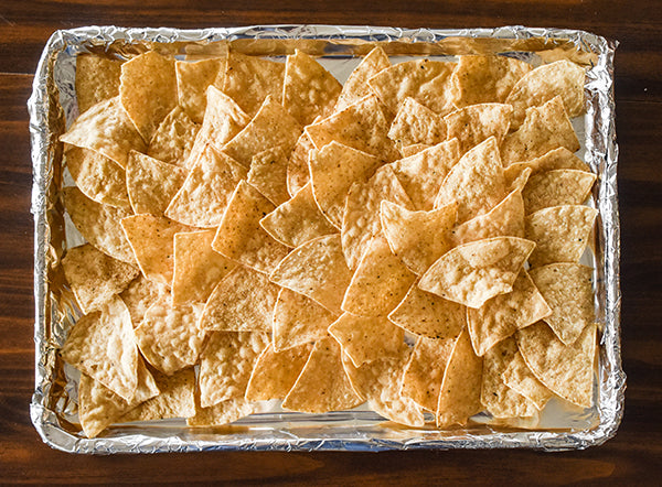 tortilla chips spread evenly on baking sheet