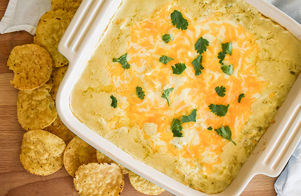 Green Chile Chicken Enchilada Party Dip in baking dish ready to eat with tortilla chips