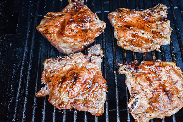red pepper jelly glazed on grilled pork chops on the grill