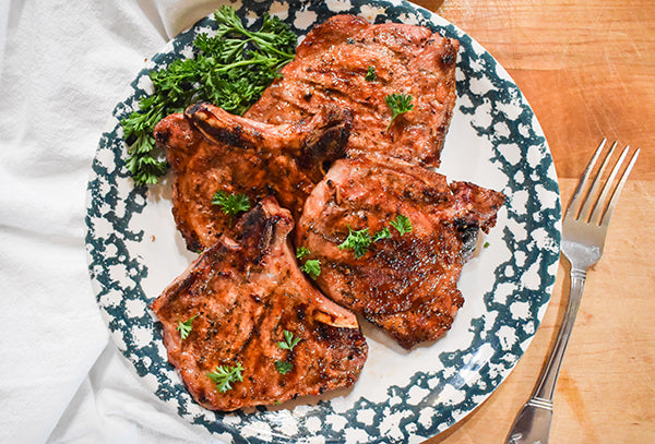 grilled sweet and spicy pork chops on plate with parsley garnish