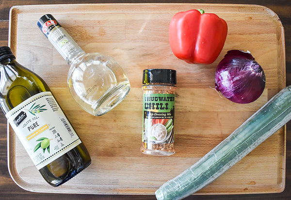 ingredients for cucumber and red bell pepper salad, olive oil, white wine vinegar, cucumber, red bell pepper, red onion, and chugwater chili dip & dressing mix