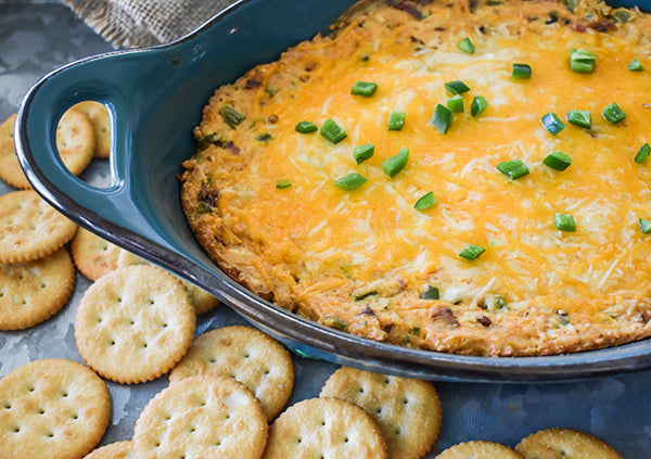 Bacon Jalapeno Popper dip in baking dish with crackers ready to eat