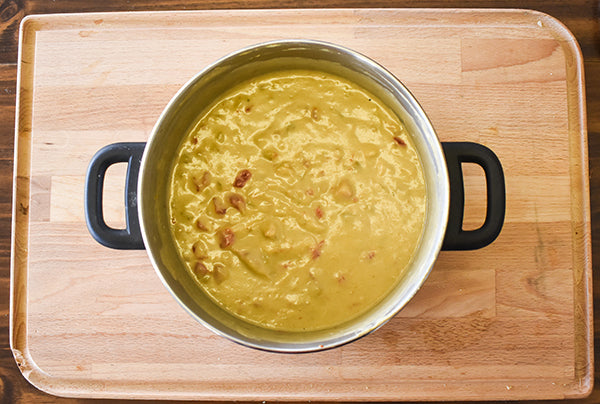 creamy green chile enchilada sauce in pot ready to ladle over chicken enchiladas