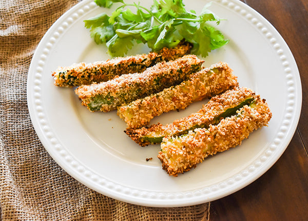 Baked zucchini fries on plate with cilantro garnish 