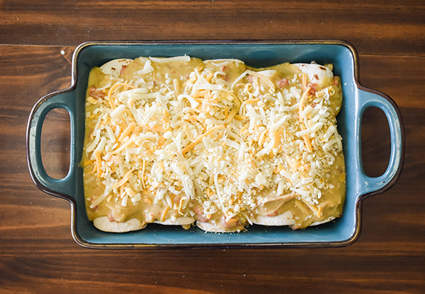 chicken enchiladas in creamy green chile sauce ready to be covered with foil and baked at 350 for 30 minutes