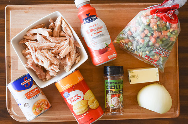 ingredients for chicken and biscuit bubble up shredded chicken, chicken broth, can of flaky biscuits, mixed vegetables, heavy cream, butter, onion, and chugwater chili dip and dressing mix