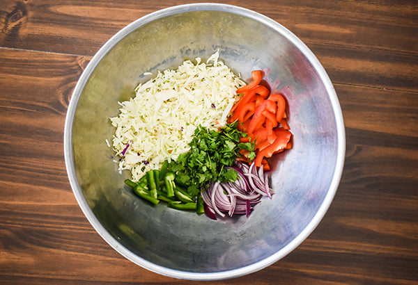 coleslaw mix, sliced red bell pepper, sliced red onion, sliced jalapeno, and chopped cilantro in bowl