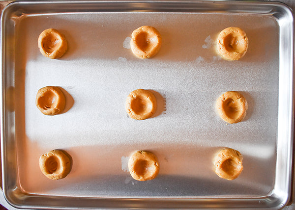 cornmeal cookie dough with thumbprints on cookie sheet
