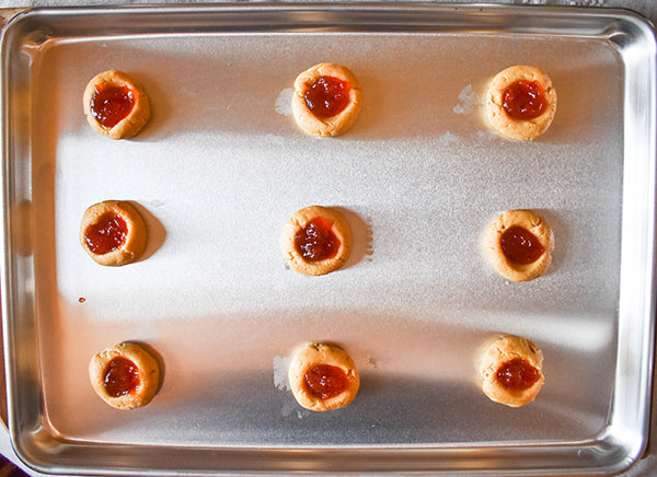 red pepper jelly added to thumbprint cookies on cookie sheet