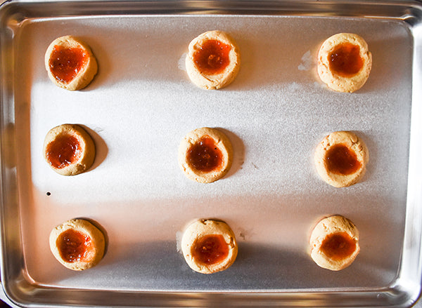 baked red pepper jelly thumbprint cookies on cookie sheet