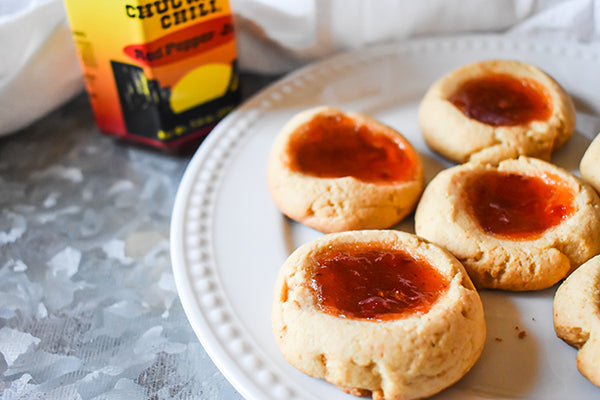 Red pepper jelly thumbprint cookies on a plate with jar of chugwater chili red pepper jelly