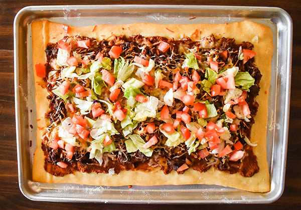 diced tomatoes and lettuce added to top of baked taco pizza