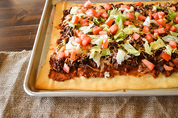 Taco Pizza with diced tomatoes and lettuce on top