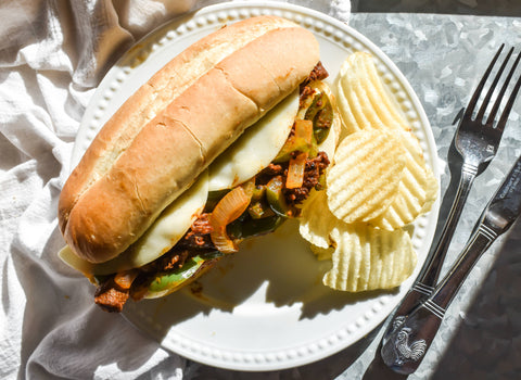 Photo of Philly Cheesesteak Sandwich on plate with chips