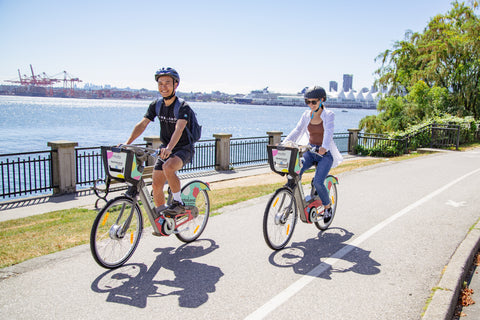 Two people biking the Vancouver Seawall on E-bikes
