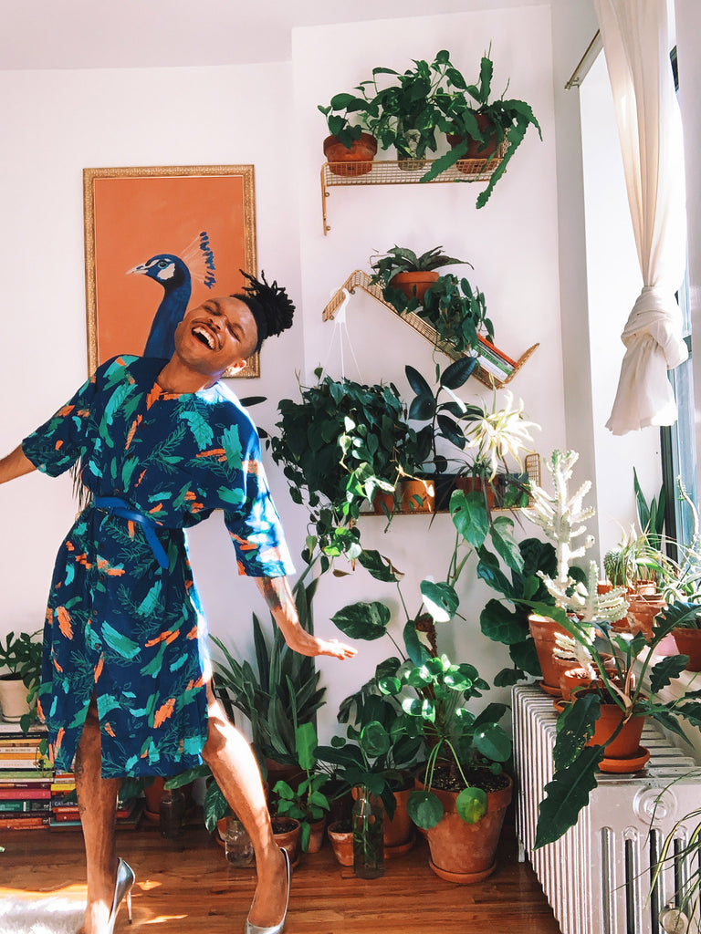 Christopher AKA The Plant Kween wears a royal blue tunic dress with a colorful orange and green botanical print