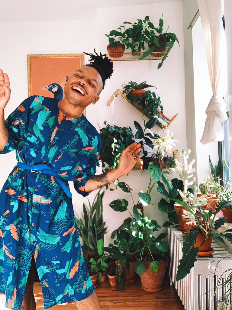 Christopher AKA the Plant Kween wears a blue tunic dress with a hand-printed botanical motif