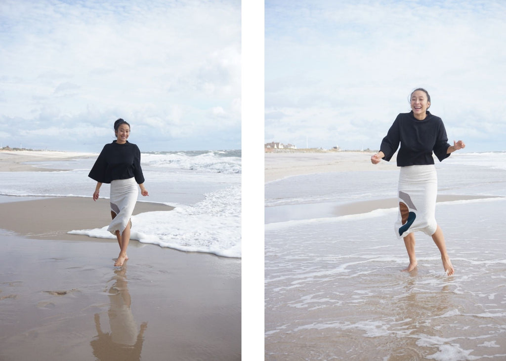 Nadya pictured playing in the waves wearing our soft jorani zero waste sweatshirt in black and our jorani sweatshirt material skirt in cream with hand sewn appliqué. https://tonle.com/collections/tops/products/jorani-sweatshirt