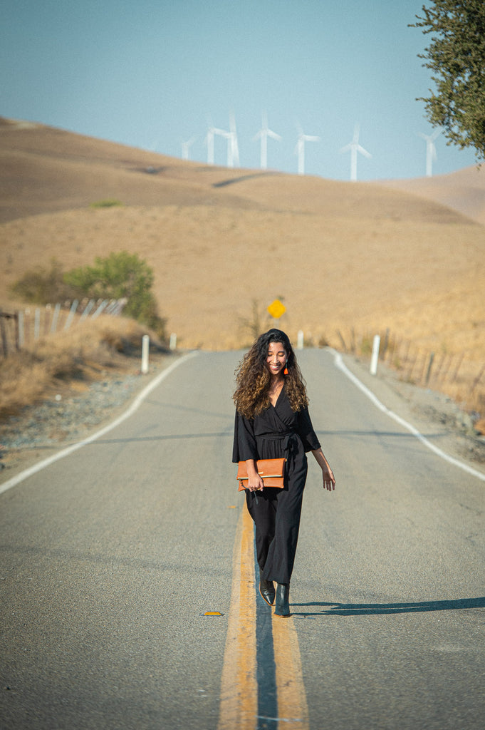 Kristy walking in front of a wind farm wearing a black vanna jumpsuit by tonlé