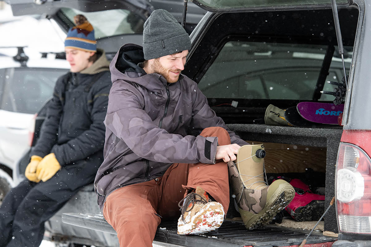 Man getting dressed for skiing on truck tailgate