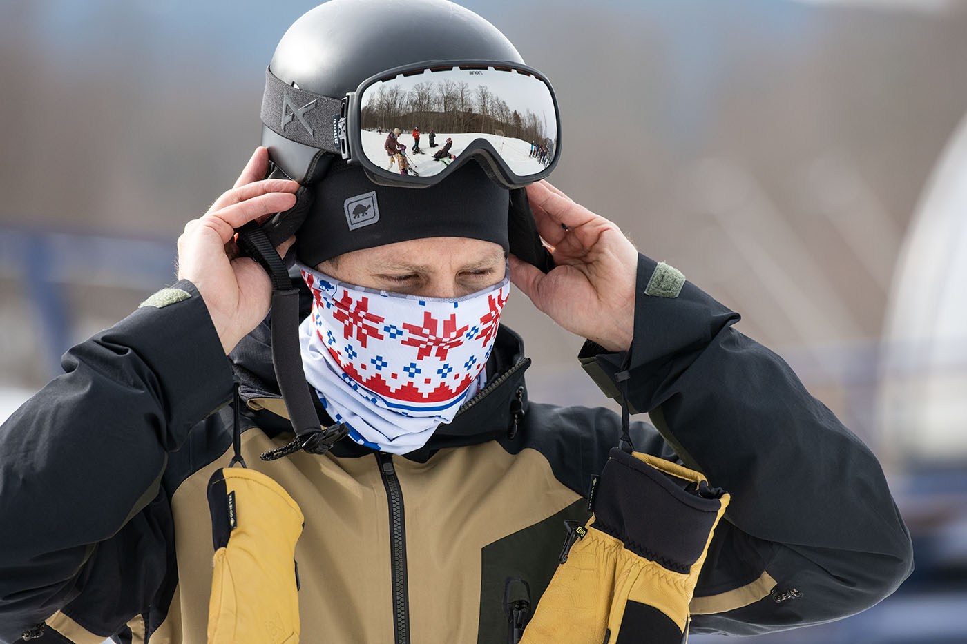 photo of skier putting on helmet and wearing a neck gaiter over face