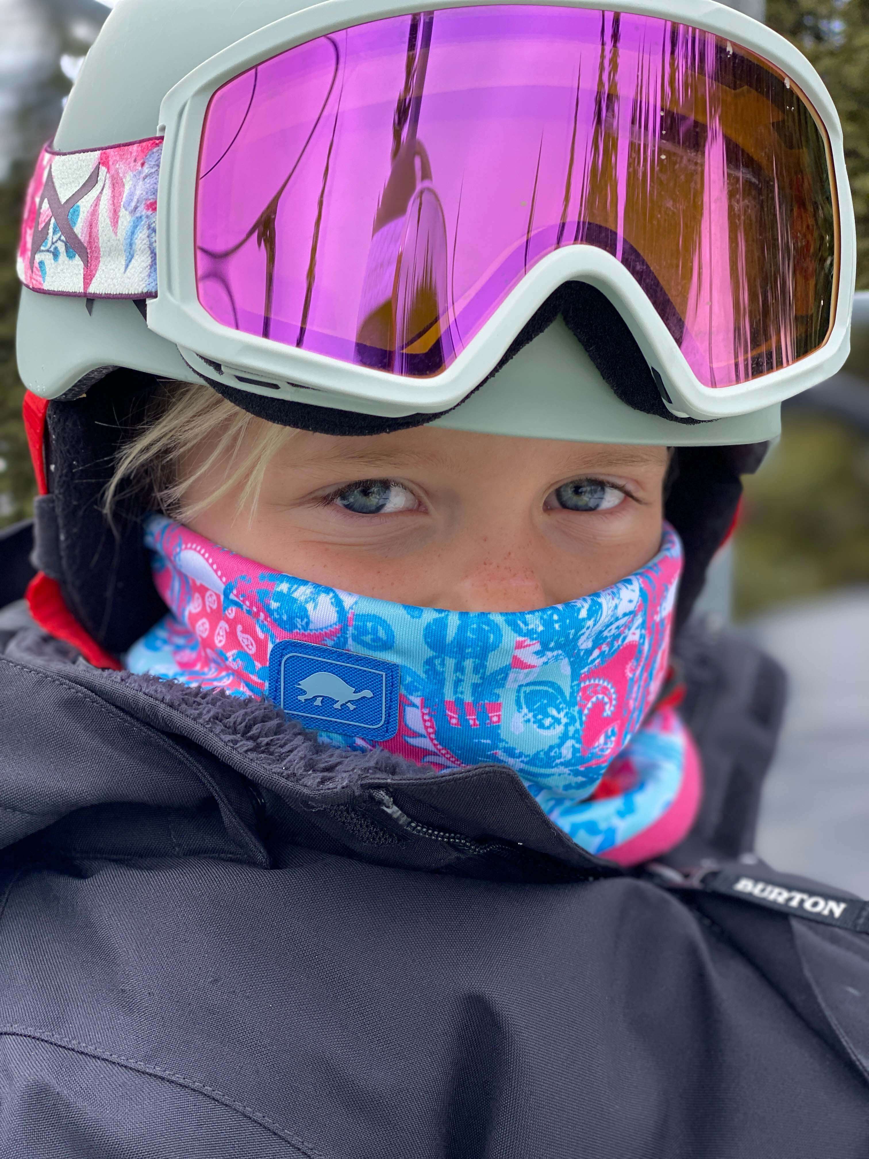 Child looking at camera with neck warmer and ski helmet