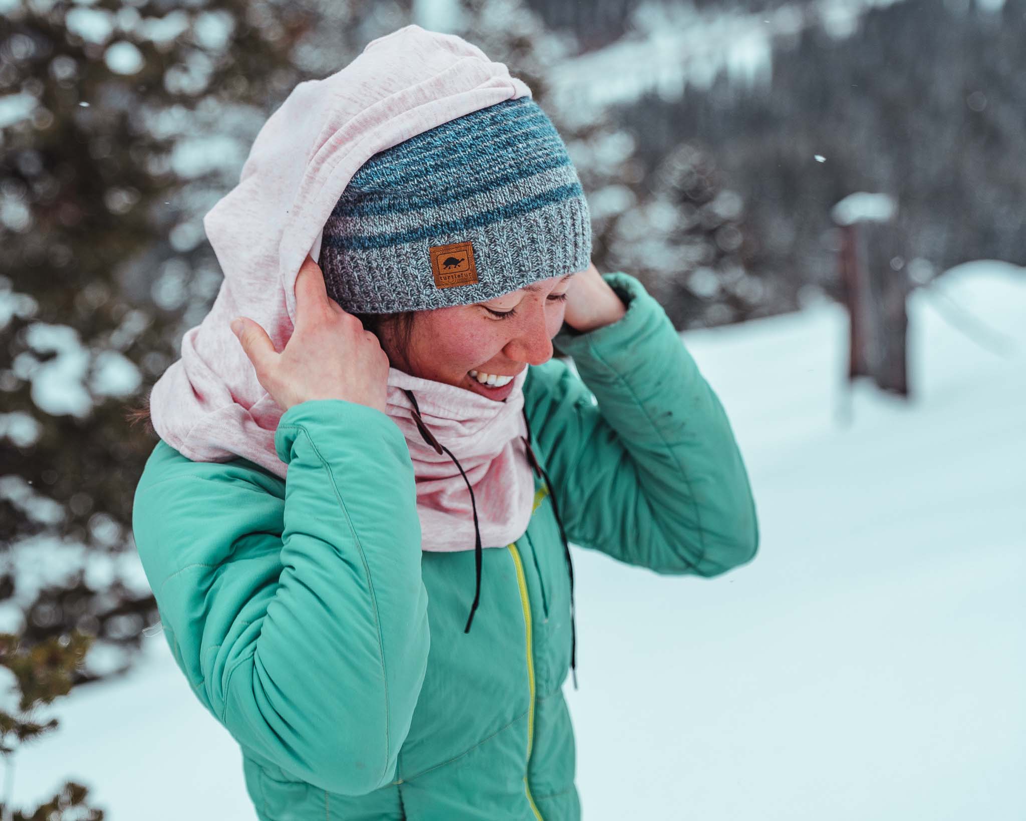 woman adjusts overhood in a field of snow