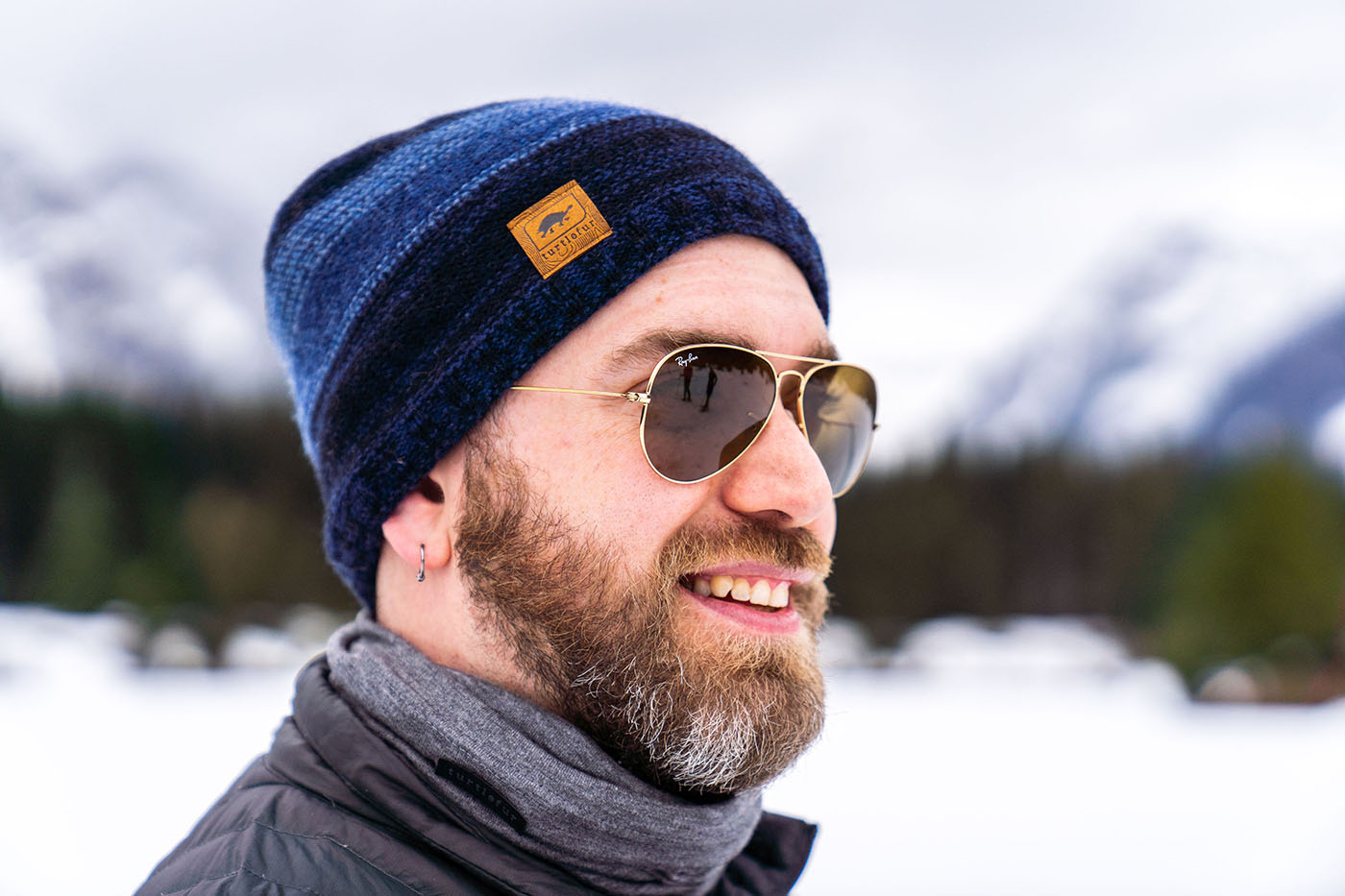 man poses wearing beanie with snow in background