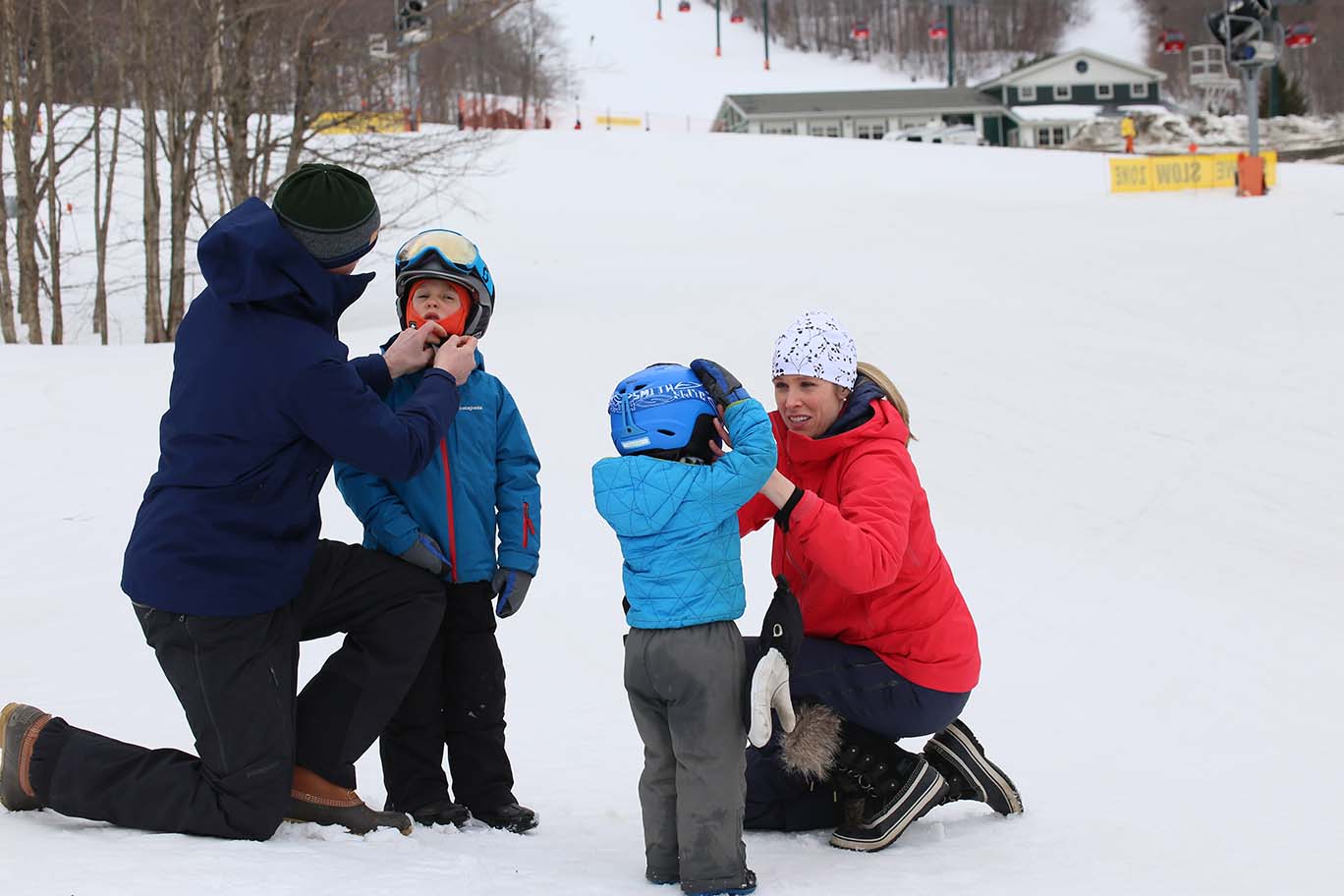 Parents adjusting ski helmets on children