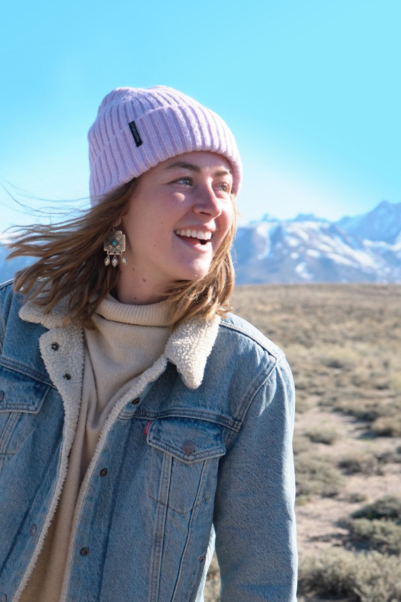 girl posing in front of mountain backdrop wearing a beanie