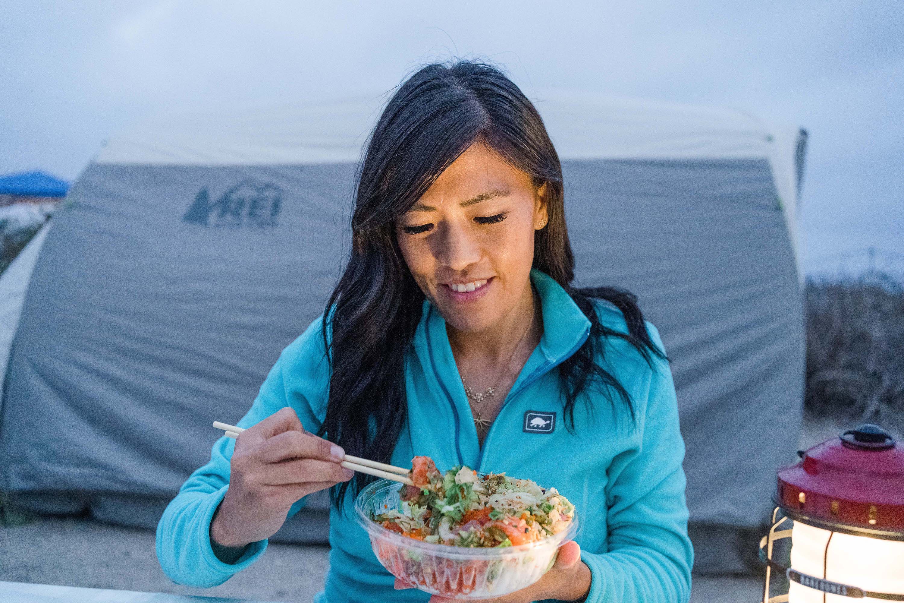 Woman outside tent eating salad