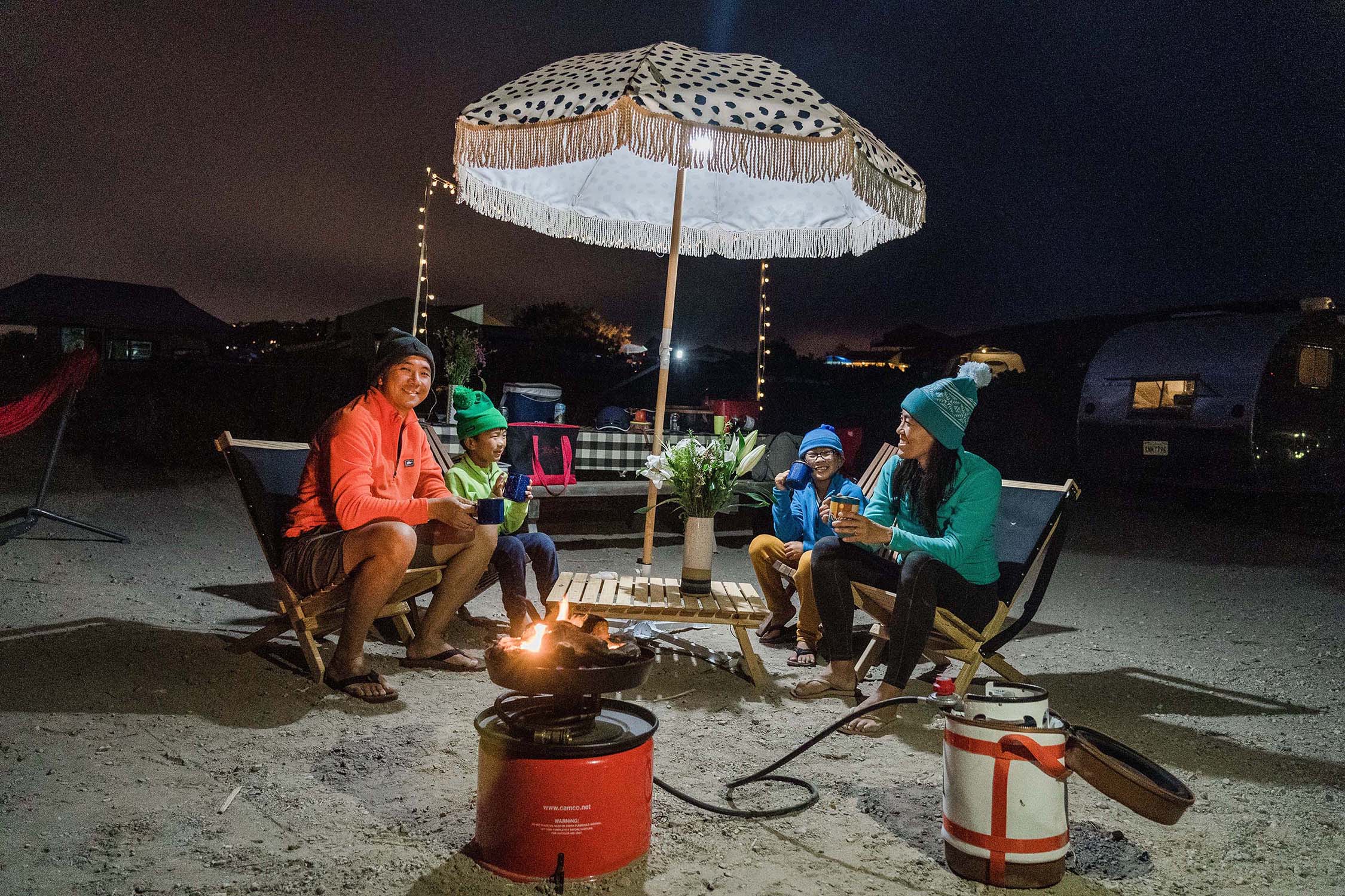 Family of four sitting around fire glamping