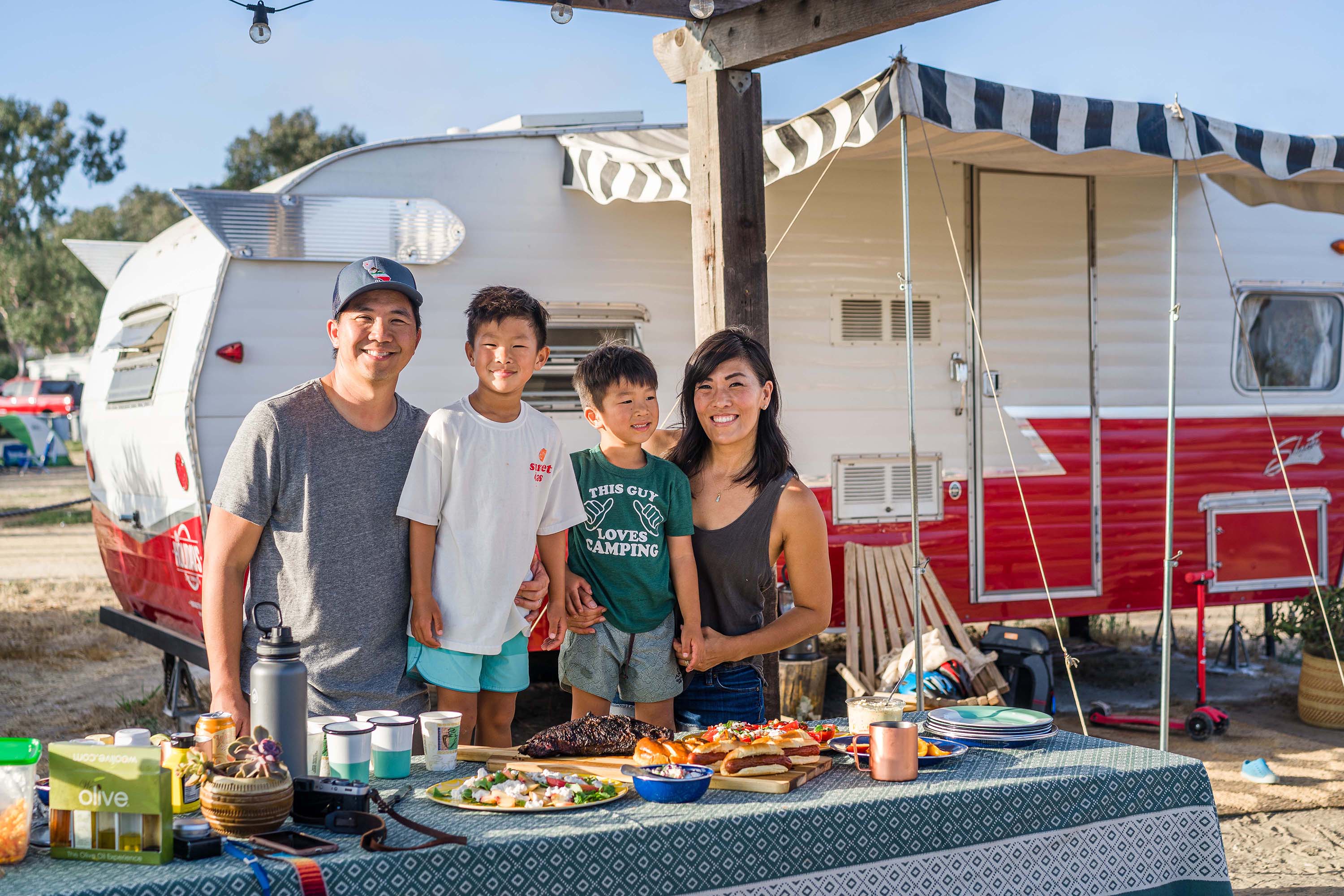 Family posing in front of camper glamping