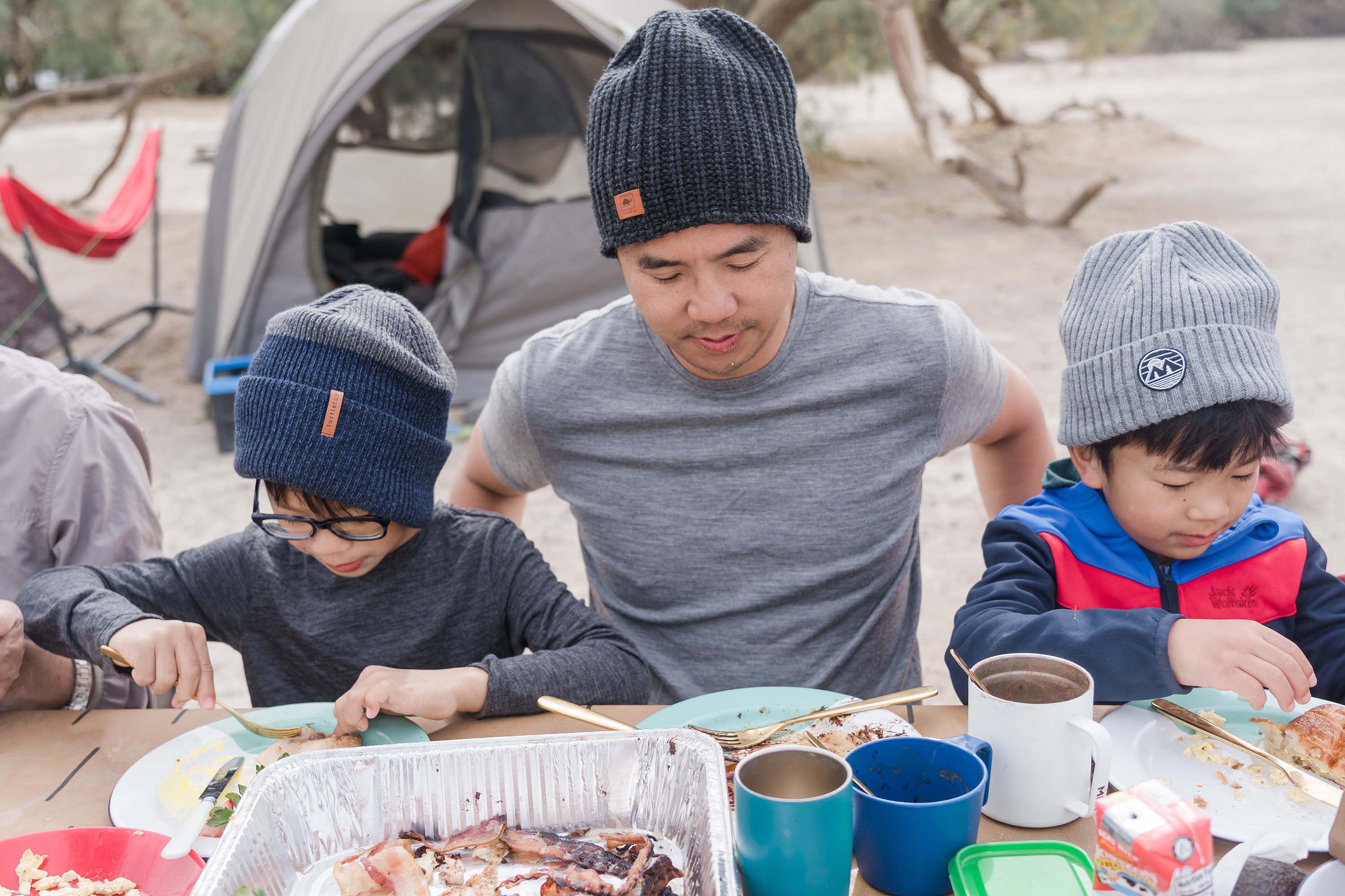 Father and kids sitting at table eating camping