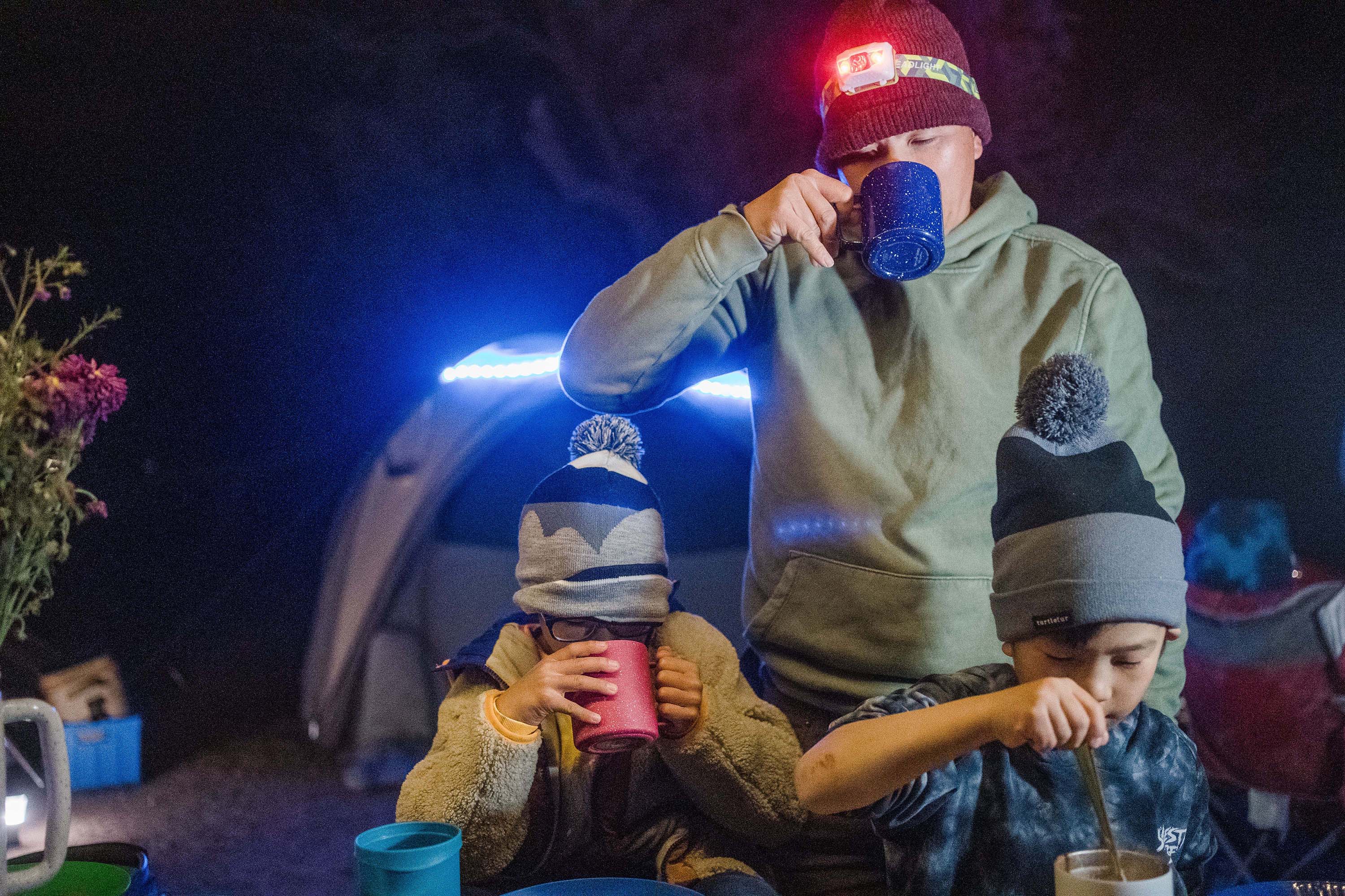 Family camping drinking hot cocoa at night