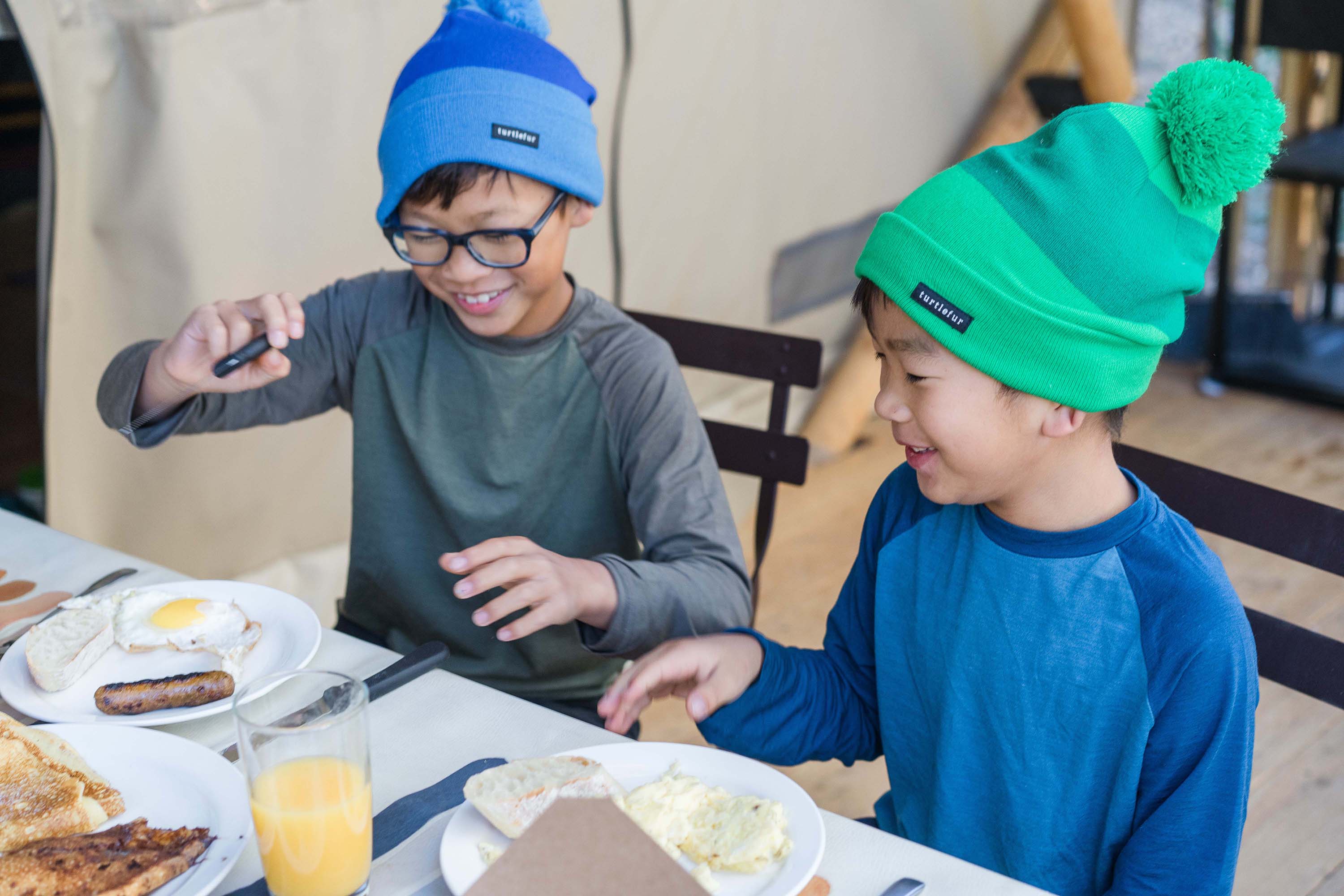 Two boys in glamping tent eating breakfast