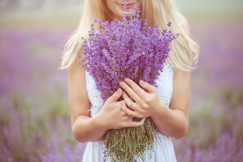 a girl with an armful of lavender standing in a lavender field