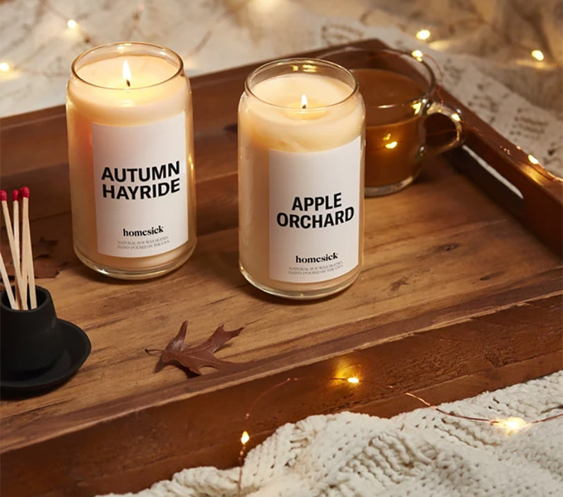 a homesick autumn hayride and an apple orchard candle on a wooden tray