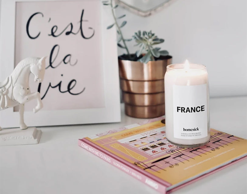 a homesick france candle next to a framed canvas that says cest la vie