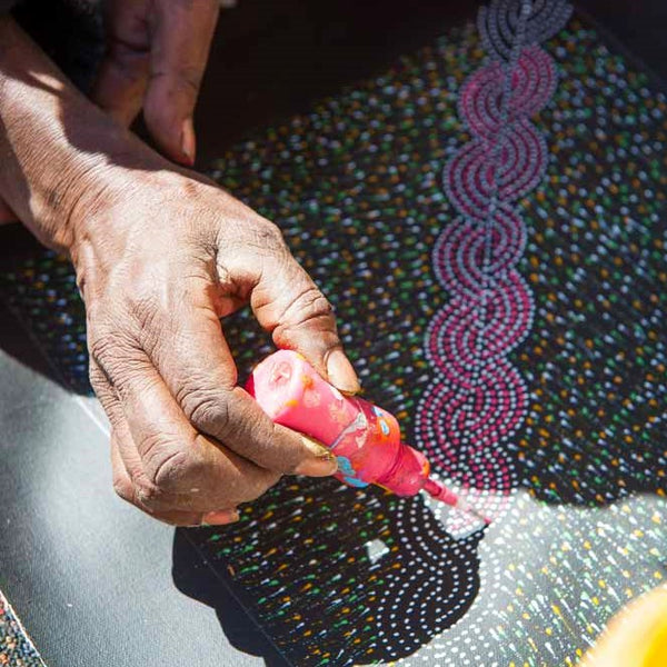 Die Aborigine-Künstlerin Elizabeth Kunoth Kngwarreye malt Blumen mit einer Flasche