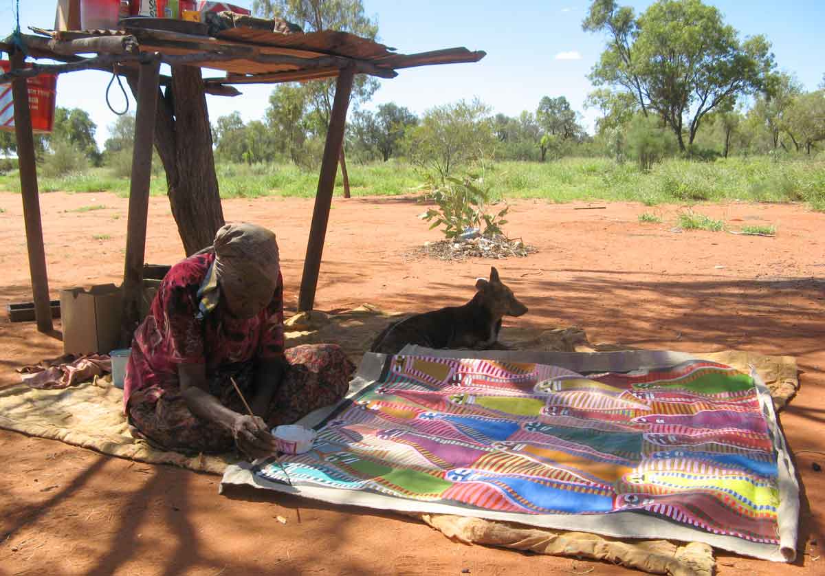 Angelina Ngale malt auf einer Decke