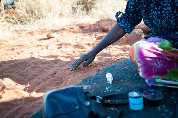 Die Aborigine-Künstlerin Elizabeth Kunoth Kngwarreye zeichnet Symbole in den Sand