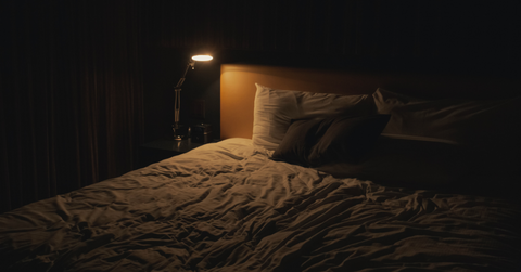 wooden bed with a bedside lamp at night