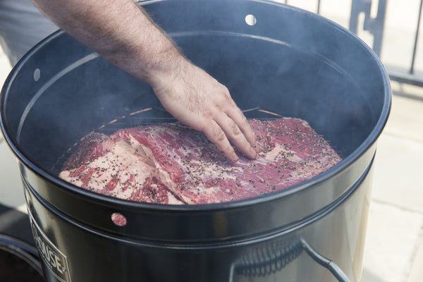 placing the brisket over Fogo All Natural Premium Lump Charcoal