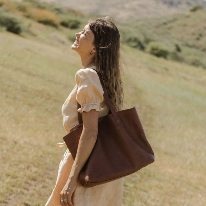 Woman in a field carrying Tecovas leather tote bag