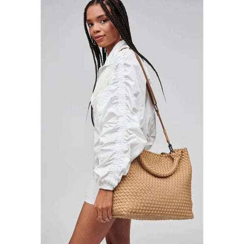 a model in a white shirt carrying a beige woven tote bag